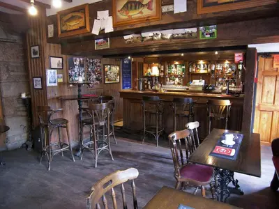 a bar in a restaurant with wooden walls and stools at Lion and Unicorn Hotel in Thornhill