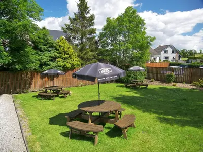 a picnic table and benches with an umbrella at Lion and Unicorn Hotel in Thornhill