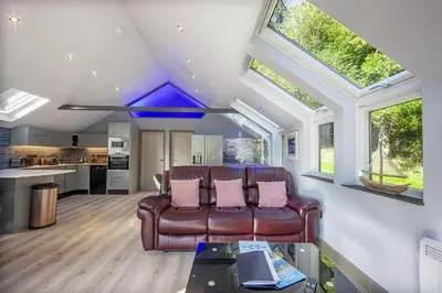 a living room with a leather couch and some windows at Dundonald Landing Palms 2 in Oban