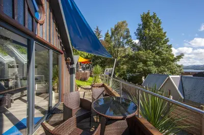 a patio with a table and chairs on a balcony at Dundonald Landing Palms 1 in Oban
