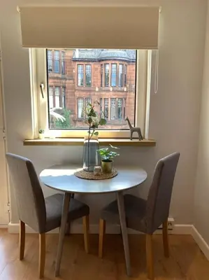 a dining room table with chairs and a window at Rustic Top Floor West End Pad With Balcony, Parking next to Byers Road, Aston Lane, Glasgow Uni in Glasgow