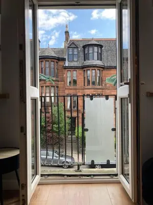 a view of a building from an open window at Rustic Top Floor West End Pad With Balcony, Parking next to Byers Road, Aston Lane, Glasgow Uni in Glasgow
