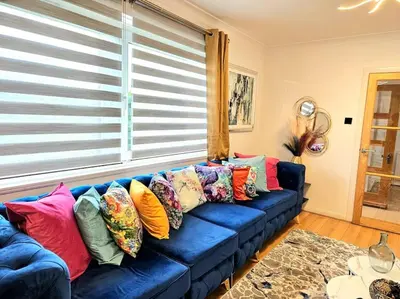 a blue couch with colorful pillows in a living room at 3 Bed House with 6 Beds by Sensational Stay in Edinburgh