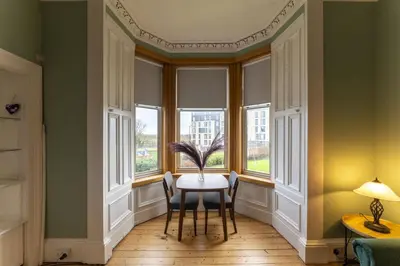 a dining room with windows and a table with a plant at Ochil View in Stirling