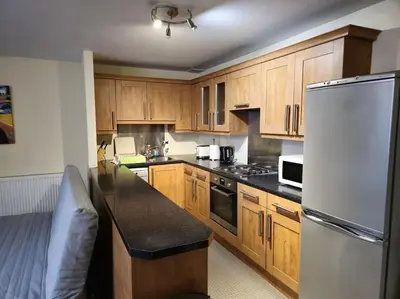 a kitchen with wooden cabinets and a white refrigerator at 2 Bedroom Modern stylish Apt in Glasgow City Centre in Glasgow