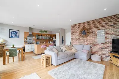 a living room with a white couch and a brick wall at Luxury Huge Modern Open Plan 2Bedroom Flat - Free Private Parking & Balcony located at the OVO Hydro and SEC Centre in Glasgow