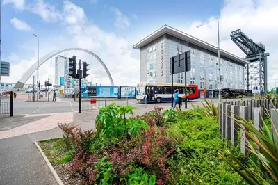 a bus is parked in front of a building at Luxury Huge Modern Open Plan 2Bedroom Flat - Free Private Parking & Balcony located at the OVO Hydro and SEC Centre in Glasgow
