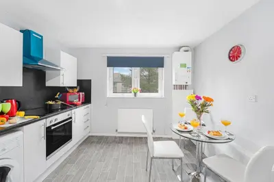 a white kitchen with a table and chairs in it at PREMIER - Maryhill Apartment in Glasgow