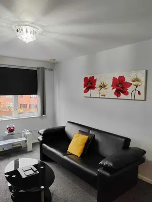 a living room with a black couch and flowers on the wall at PREMIER - Maryhill Apartment in Glasgow