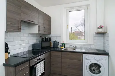 a kitchen with a sink and a washing machine at Free Parking - 2 Bedroom Flat-by Holiday Homes in Cambusnethan
