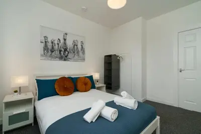 a bedroom with a blue and white bed with towels on it at Free Parking - 2 Bedroom Flat-by Holiday Homes in Cambusnethan