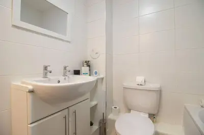 a white bathroom with a sink and a toilet at 2 bed flat near airport &parking in Paisley