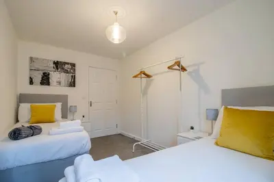 a bedroom with two beds with yellow pillows at 2 bed flat near airport &parking in Paisley
