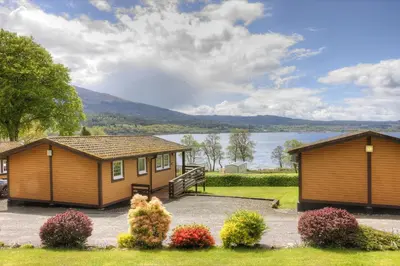two cottages with a view of a lake at Appin Holiday Homes -Caravans, Lodges, Shepherds Hut and Train Carriage stays in Appin