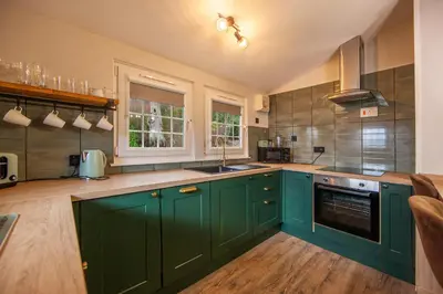 a kitchen with green cabinets and a sink at Appin Holiday Homes -Caravans, Lodges, Shepherds Hut and Train Carriage stays in Appin