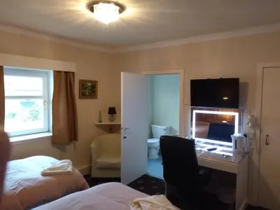 a hotel room with a bed and a desk with a mirror at Dalgair House Hotel in Callander