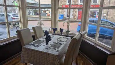 a dining room table with chairs and a table and windows at Dalgair House Hotel in Callander