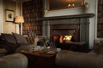 a living room with a fireplace with couches and a table at Macdonald Forest Hills Hotel & Spa in Aberfoyle