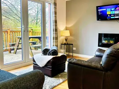 a living room with couches and a tv and a balcony at Rum in Oban