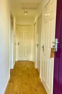 an empty hallway with white doors and wooden floors at Rum in Oban
