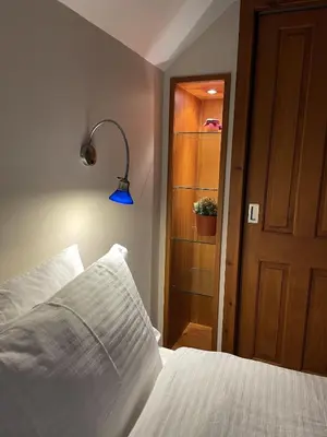 a bedroom with a white bed with a blue lamp at Craigruie Farmhouse in Balquhidder