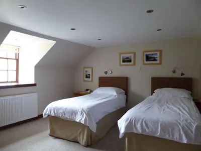 a bedroom with two beds and a window at Craigruie Farmhouse in Balquhidder
