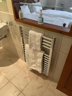 a bathroom with a towel rack next to a bed at Craigruie Farmhouse in Balquhidder