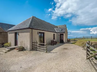 a small house on a gravel road with a fence at Eryb Cottage - Uk46883 in Kilmory