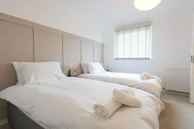two beds in a bedroom with white sheets and towels at Whiteside Apartment in Bathgate