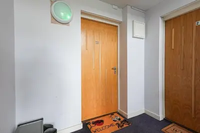a hallway with a wooden door and a clock on the wall at Whiteside Apartment in Bathgate