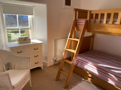a bedroom with a bunk bed and a desk at Christmas Cottage in Balmaha
