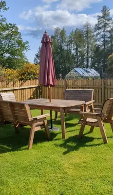 a picnic table with an umbrella and two benches at Christmas Cottage in Balmaha