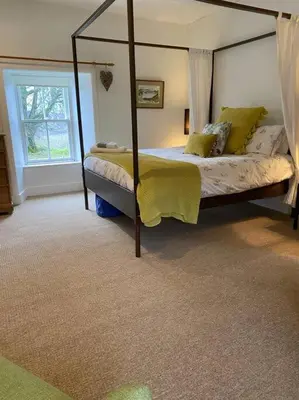 a bedroom with a canopy bed and a window at Christmas Cottage in Balmaha