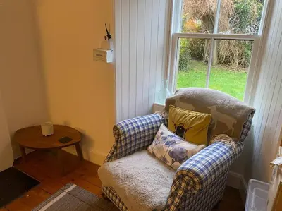 a living room with a chair and a window at Christmas Cottage in Balmaha