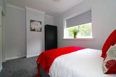 a bedroom with a large bed with red pillows and a window at Signature - Huntley House in Glasgow