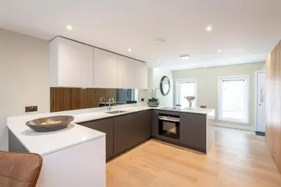 a kitchen with white cabinets and a bowl on the counter at Dragon Suites - City Centre 2 Bed Luxury Mews House in Edinburgh