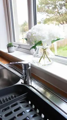 a vase filled with white flowers sitting on a window sill at Burns House in Livingston