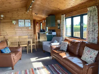 a living room with couches and a kitchen in a cabin at The Lodge at Blackhill Farm in Carluke