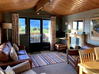 a living room with leather couches and a television at The Lodge at Blackhill Farm in Carluke