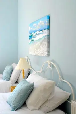 a bed with pillows and a picture of the beach at 6 Killean Place in Campbeltown