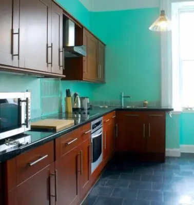 a kitchen with wooden cabinets and a green wall at 6 Killean Place in Campbeltown