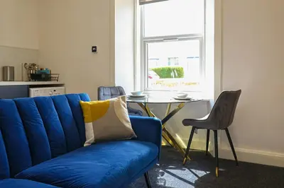a blue couch in a living room with a table at Meadowfoot Haven in West Kilbride