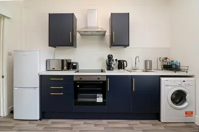 a kitchen with blue cabinets and a white refrigerator at Meadowfoot Haven in West Kilbride
