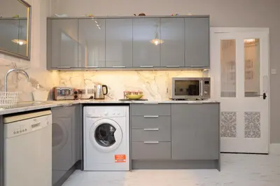 a kitchen with a washing machine and a washer at Janeville Holiday Apartment in Ardrishaig
