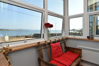 a room with windows with a chair and red pillows at Janeville Holiday Apartment in Ardrishaig