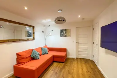 a living room with an orange couch and a tv at 4 Bed complete Home in Edinburgh Near Airport in Edinburgh