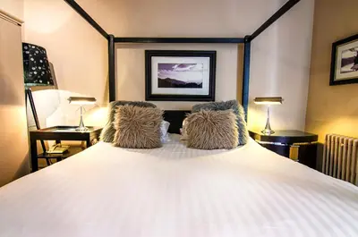 a bedroom with a large white bed with two lamps at Strathaven Hotel in Strathaven