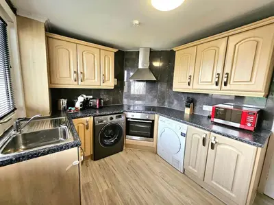 a kitchen with wooden cabinets and a sink and a dishwasher at 4 bed house With 6 Beds in Edinburgh