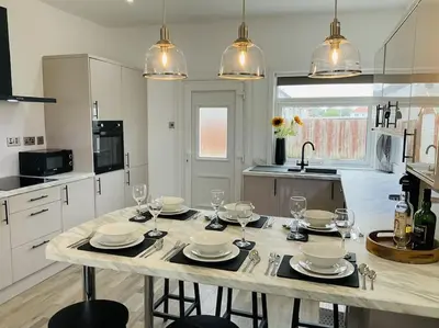 a kitchen with a table with plates and wine glasses at Harling House - Prestwick - 4 bedrooms in Prestwick