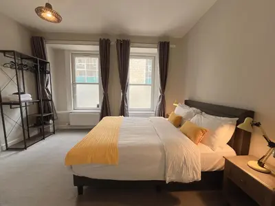 a bedroom with a large bed and two windows at Two bed apartment in Edinburgh